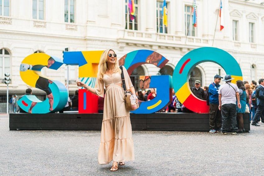 Une femme en robe se tient devant une sculpture colorée sur laquelle est inscrit le mot « STOP ». 1