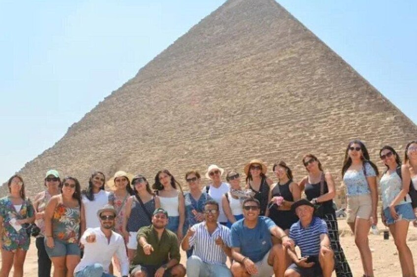 A group of people posing in front of a pyramid. 3