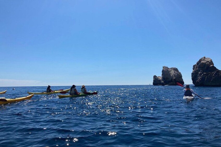 Un groupe de personnes pratiquant le kayak par une journée ensoleillée, avec de grandes formations rocheuses en arrière-plan. 4