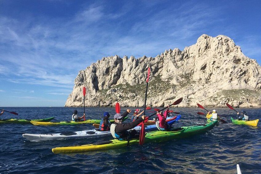 Des personnes pratiquent le kayak sur une étendue d’eau calme, avec une falaise rocheuse en arrière-plan. 3