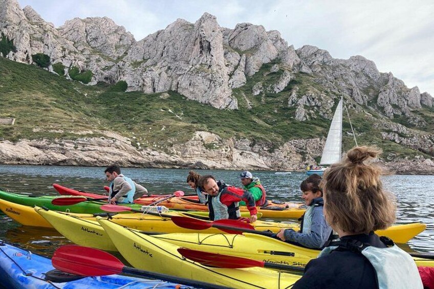 Des personnes pratiquent le kayak sur un lac, avec des montagnes rocheuses en arrière-plan. 2