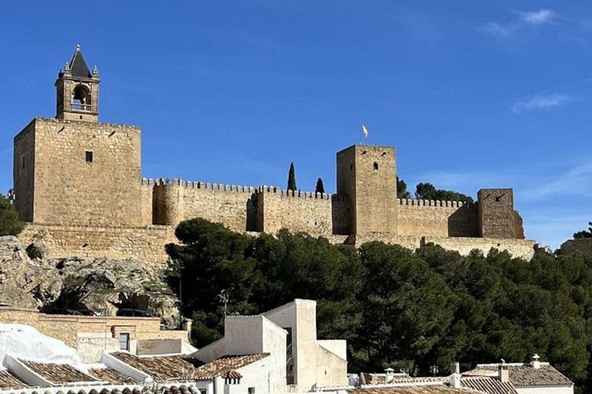 A historic stone fortress with a prominent bell tower and crenellated walls. 1