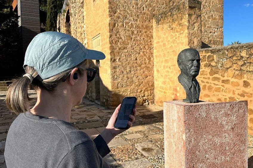 A person taking a photo of a bust sculpture with a smartphone. 4