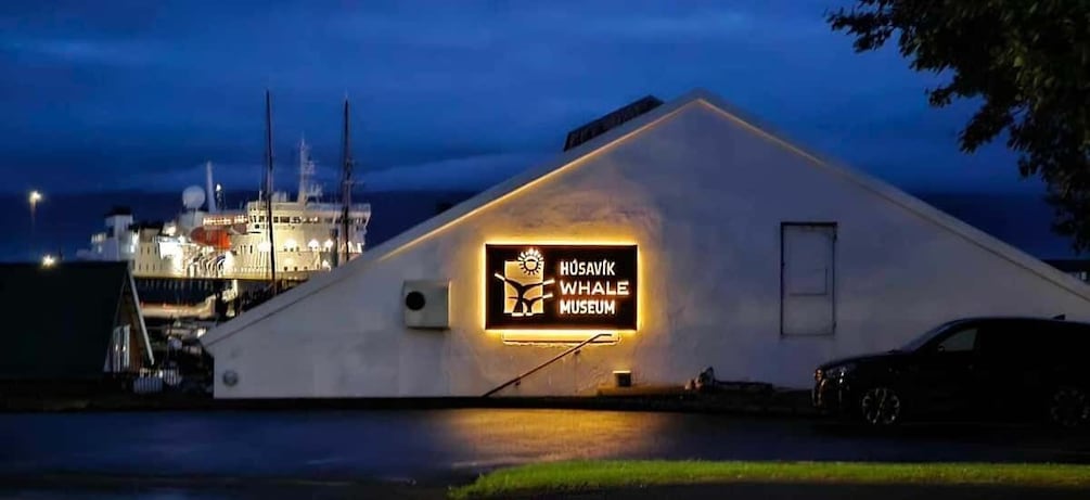 A building with a sign reading "Húsavík Whale Museum" at dusk. 2