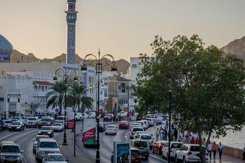 A busy urban street with cars, pedestrians, and a prominent minaret. 2