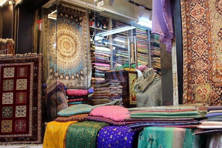 A variety of colorful textiles and rugs displayed in a shop. 1