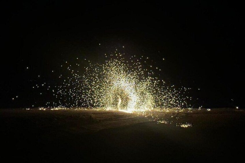 Une scène nocturne avec une source de lumière vive et un grand nombre de petites particules ou d’étincelles lumineuses. 5