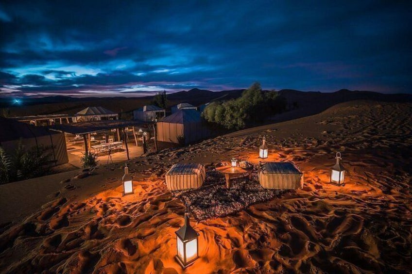 Un campement dans le désert au crépuscule, avec des tentes et des lanternes. 2