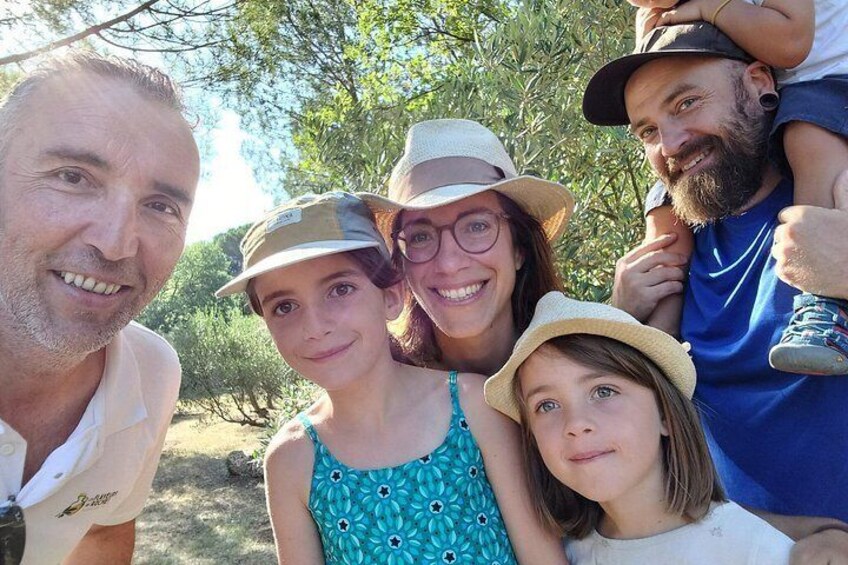 A family outdoors, possibly in a park or natural setting, with trees and greenery in the background. 3