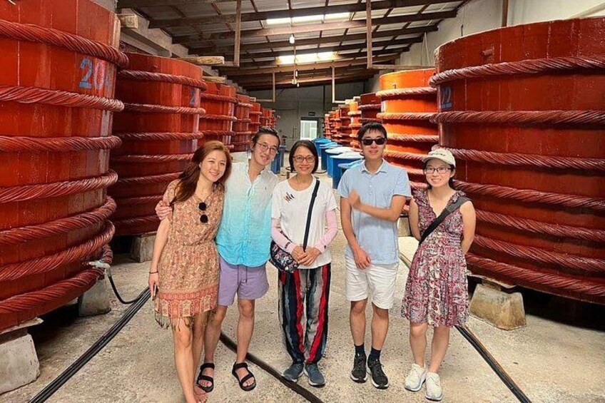 A group of people standing in a warehouse with large red cylindrical tanks. 4