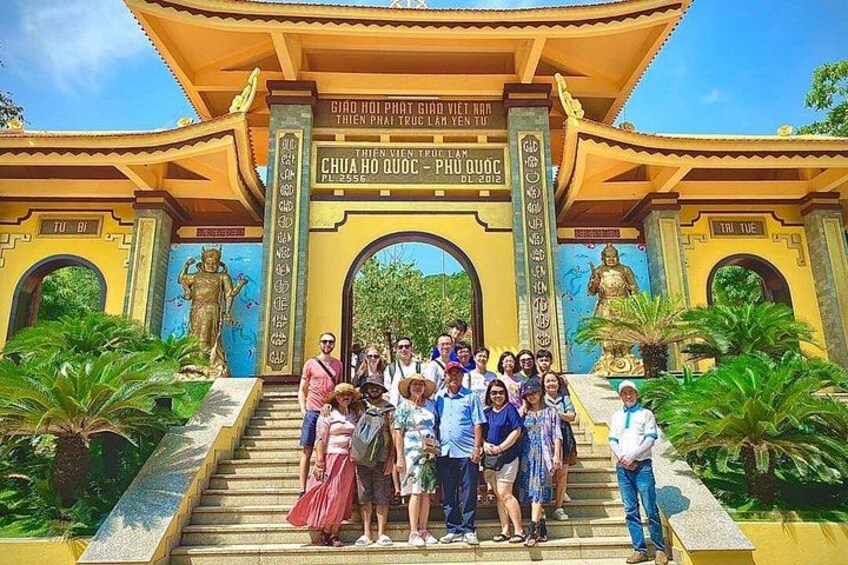 A group of people standing in front of a temple entrance with a large statue and inscriptions. 3