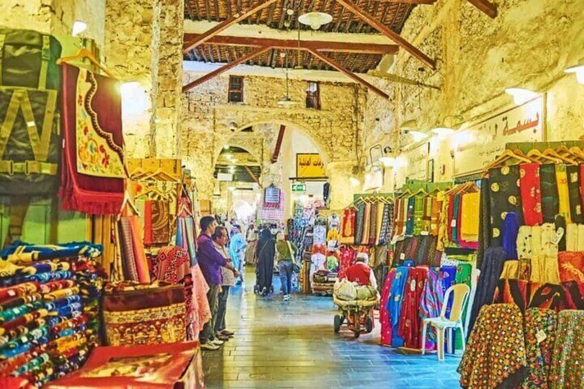 Un mercado animado con textiles y alfombras de colores exhibidas. 5