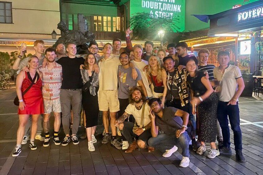 Un groupe de personnes posant pour une photo devant un restaurant dont l’enseigne est verte. 1