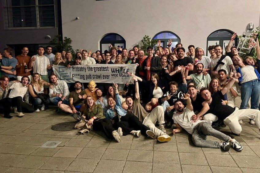 A group of people posing for a photo in an outdoor setting with a banner. 4