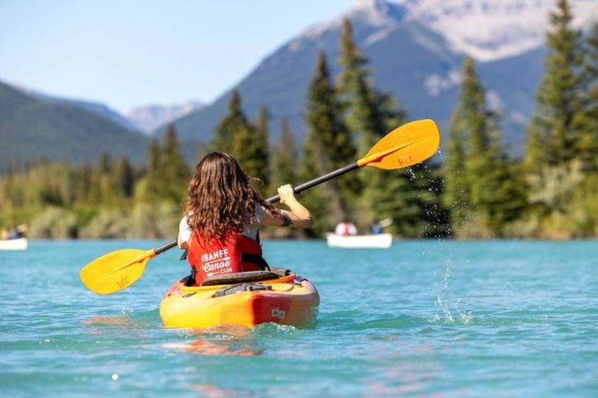 A person kayaking on a calm lake with mountains in the background. 2