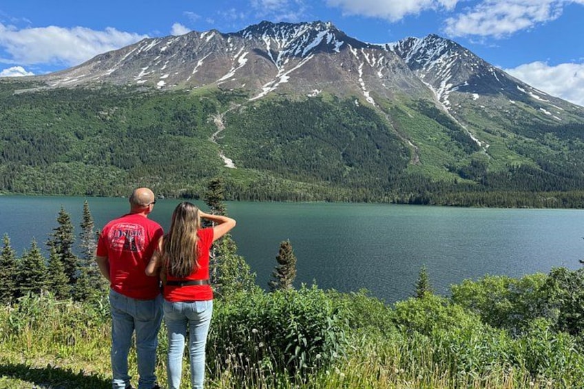 A couple standing by a lake with a mountain in the background. 3