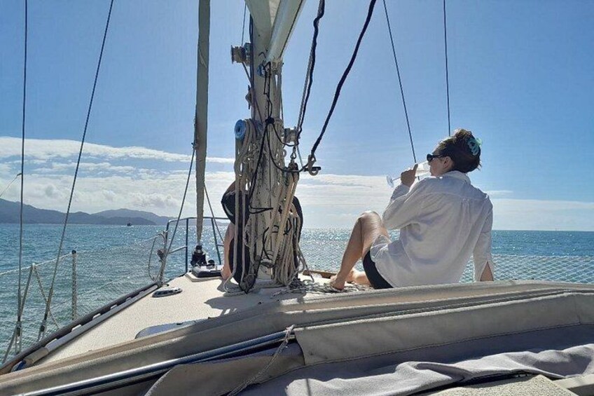 Un velero en aguas tranquilas con una persona sentada en la cubierta y otra de pie. 2