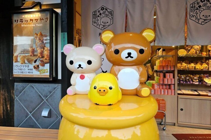 A display of plush toys, including a large brown bear, a white bear, and a yellow duck, on a yellow stand. 4