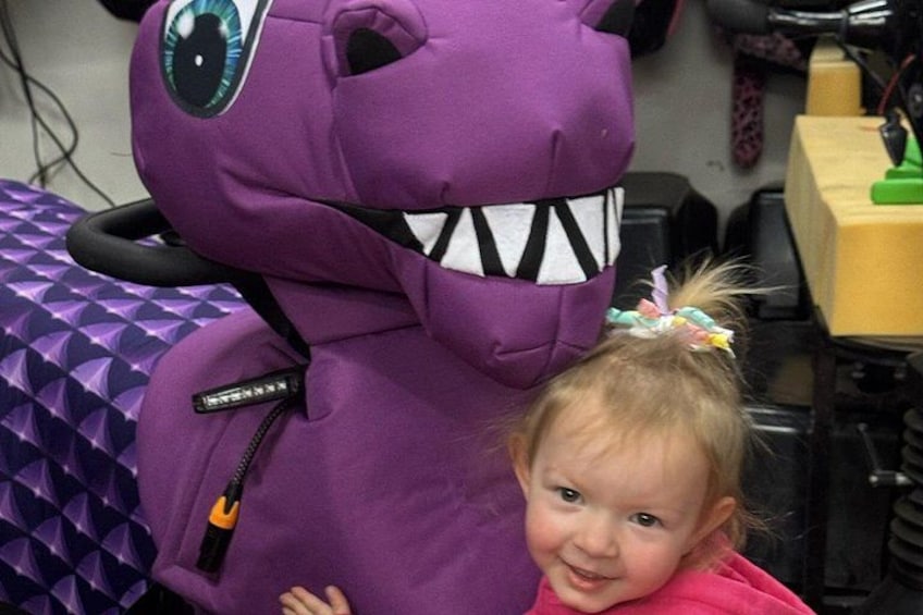 A purple creature with a zipper and a zipper pull, a child in a pink shirt, and a patterned tablecloth. 3