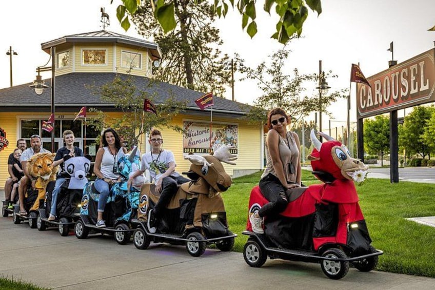A group of people on a carousel with animal figures. 5