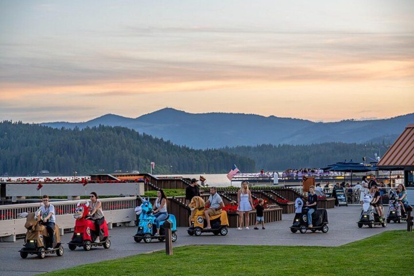 A group of people on go-karts on a track with a scenic mountain backdrop. 3
