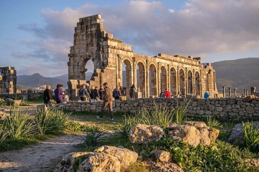 Ancient ruins with arches and columns, surrounded by tourists. 1