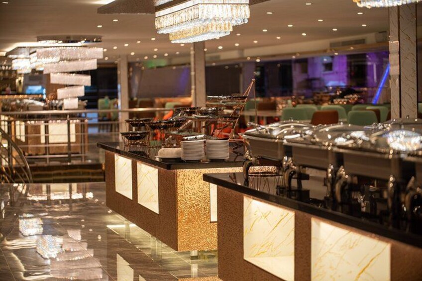 A buffet setup with multiple serving stations, a polished marble floor, and hanging crystal chandeliers. 1