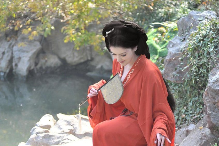 A person in traditional attire sitting by a rocky riverbank. 3