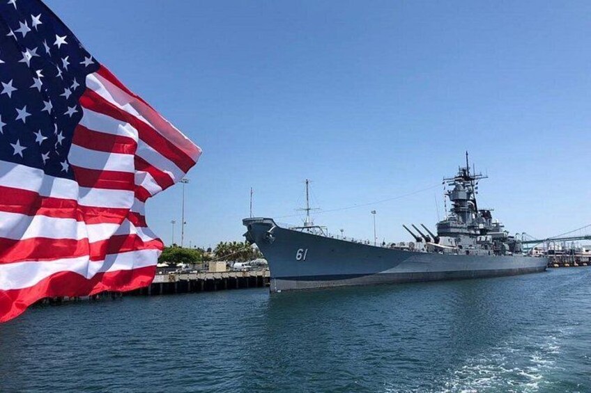 Una grande nave da guerra ormeggiata al molo, con una bandiera americana che sventola in primo piano. 1