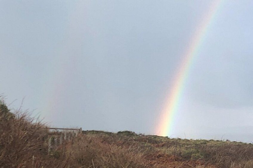 A rainbow over a grassy hill with a building in the background. 5