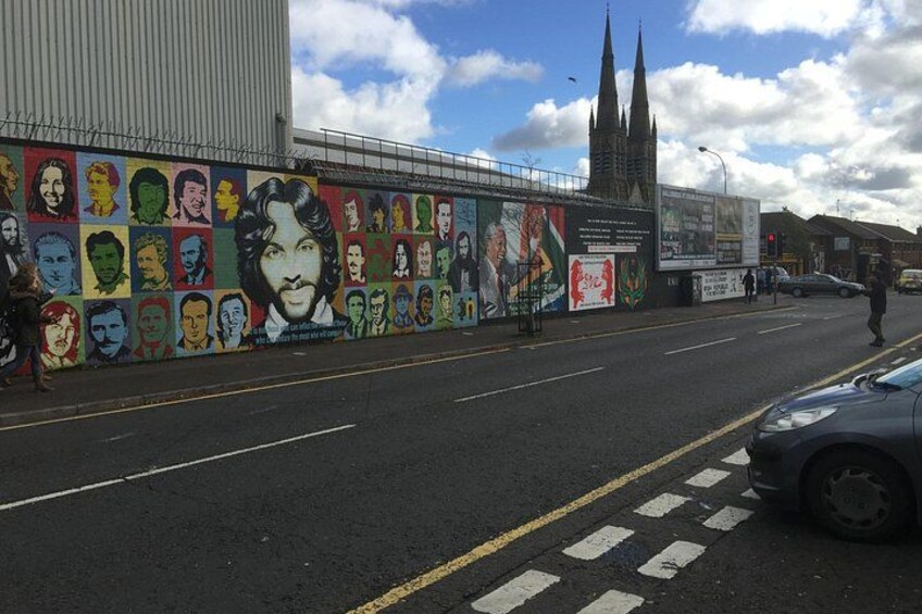 A street with a mural, a church, and a car. 4