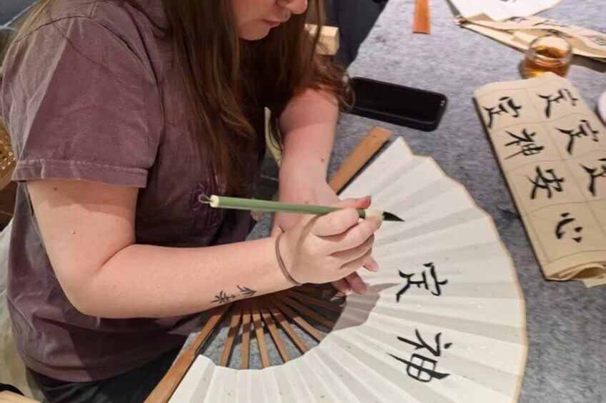 Una persona escribiendo caligrafía china en un abanico. 5