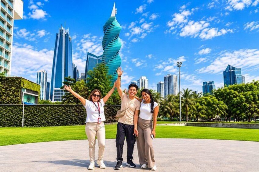 A group of people posing in front of a modern sculpture and tall buildings. 3