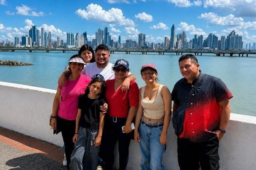 A group of people standing by a waterfront with a city skyline in the background. 4