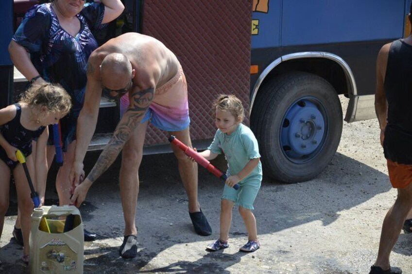 A man in a tank top and shorts, a child with a red bat, and a woman in a blue shirt. 5