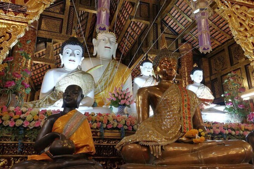 En tempelinteriör med stora Buddha-statyer och en munk i traditionell dräkt. 3