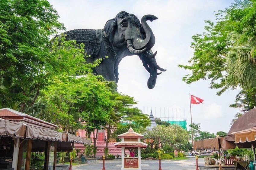 A large elephant statue, a temple, and a flag. 5