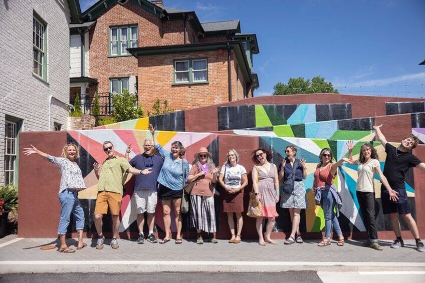 Un grupo de personas frente a un muro con un diseño geométrico llamativo. 3
