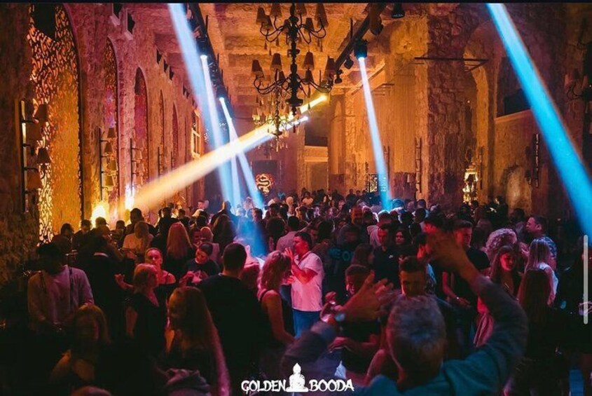 Un espacio interior concurrido, con paredes de piedra y candelabros. 1
