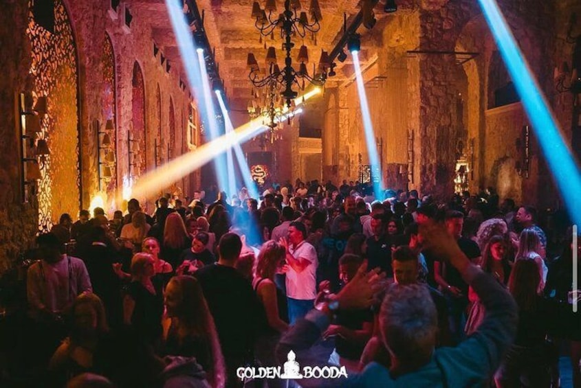 Un espacio interior concurrido, con arcos de piedra y candelabros. 3