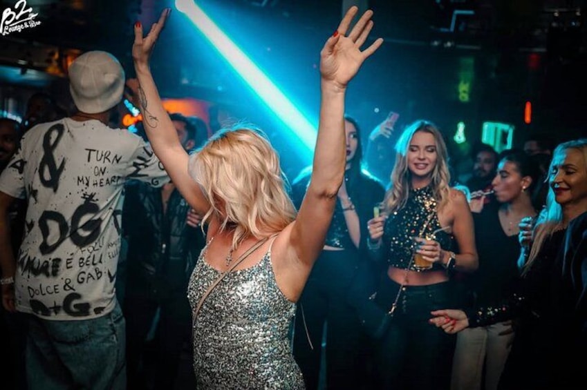 Una persona bailando en un club con gente en el fondo. 5