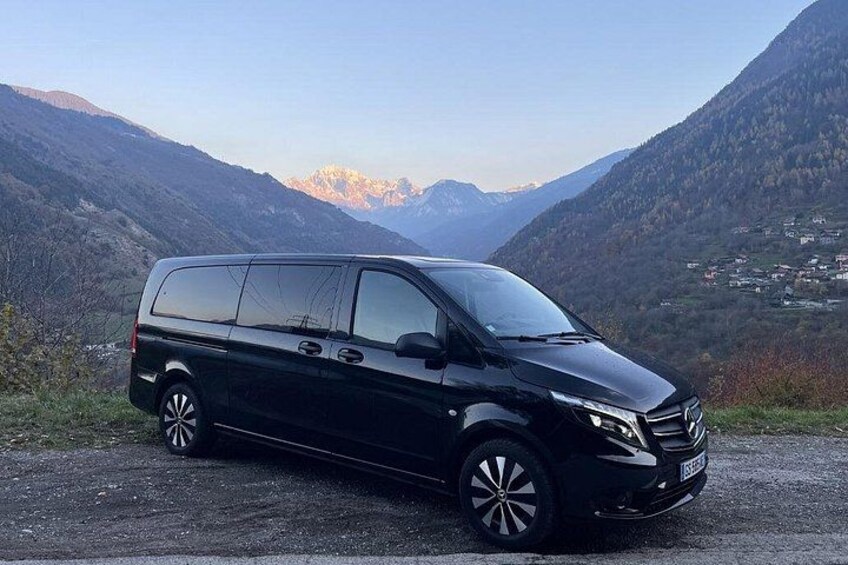 En sort minibuss parkeret på en vej med et bjergrigt landskab i baggrunden. 2