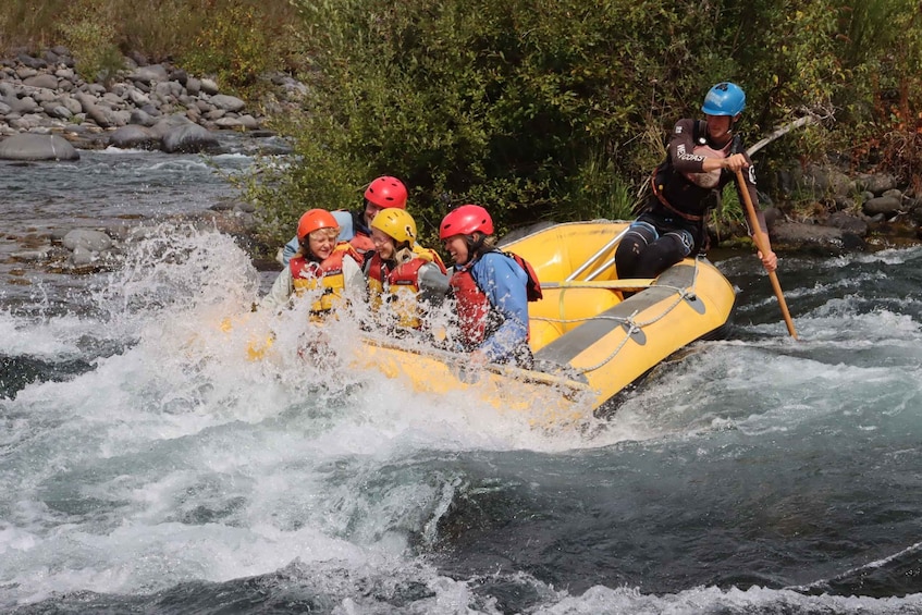 A group of people in a yellow raft navigating a river with rapids. 1