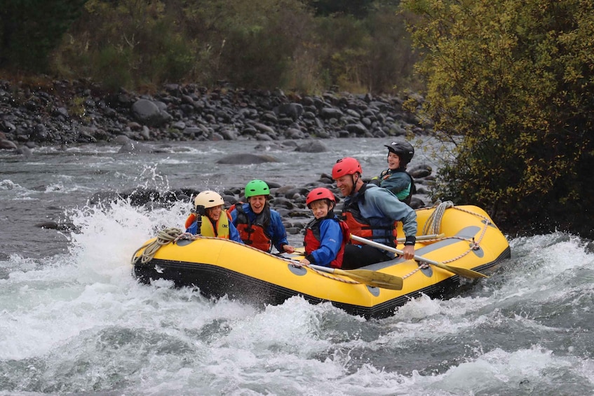 A group of people in a yellow raft navigating a river with rapids. 4