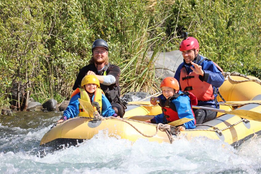 People rafting on a yellow raft in a river surrounded by greenery. 3