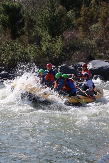 A group of people in a yellow raft navigating through a river with rapids. 2