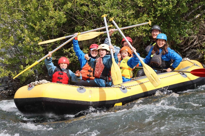 A group of people in a yellow inflatable raft on a river surrounded by greenery. 5