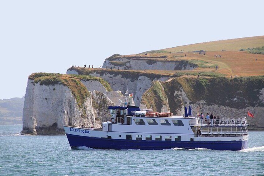A boat named 'Solent Scene' on the water near cliffs. 3