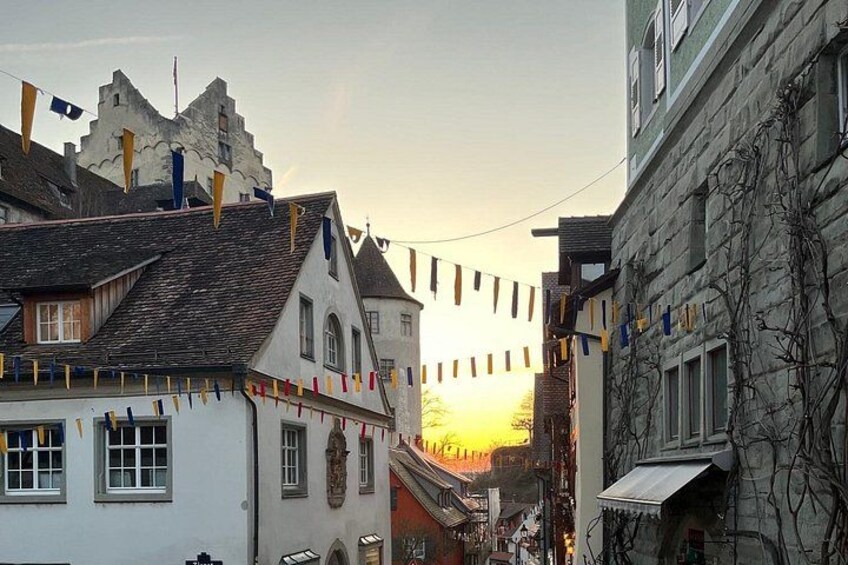 A street with buildings, a castle-like structure, and a sunset. 2