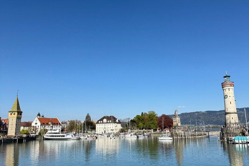 A calm river with boats, a lighthouse, and historic buildings. 1